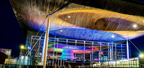 Adeilad y Senedd wedi’i oleuo yn lliwiau’r enfys.